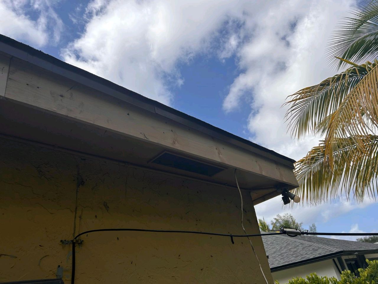 Side angle of Robert Lewis’s home with worn fascia and aging roof before replacement